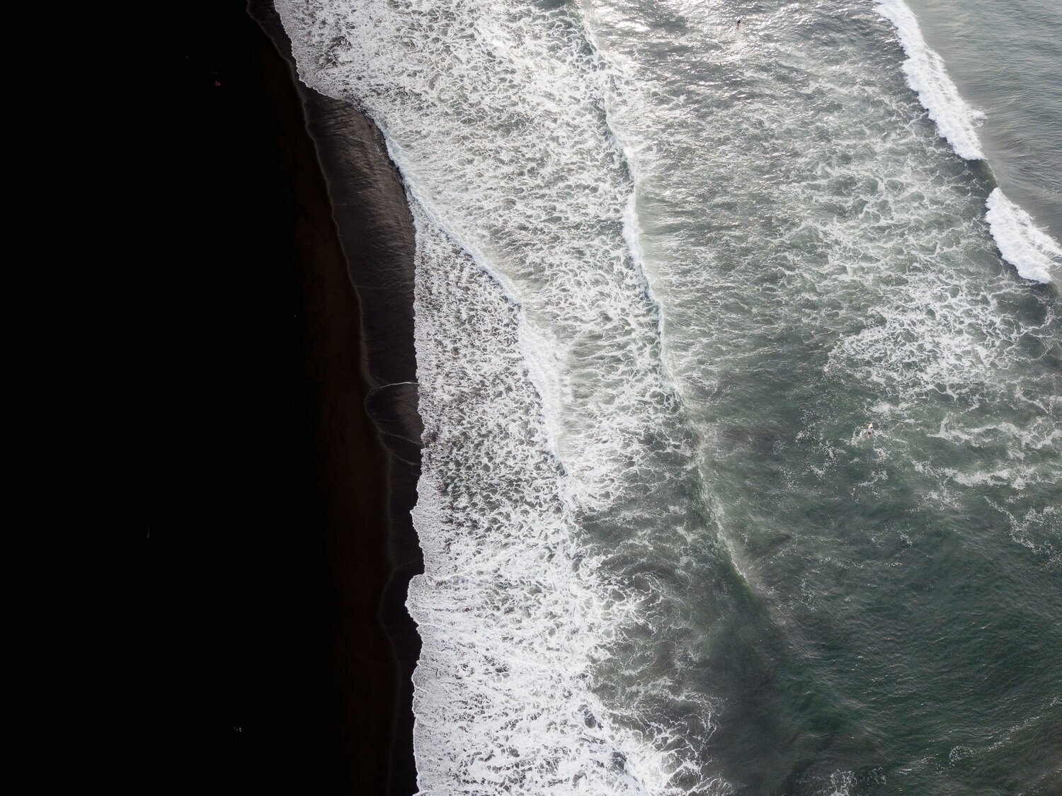 Vue aérienne d'une plage de sable noir avec vagues déferlantes. Mer agitée. Côte et océan.